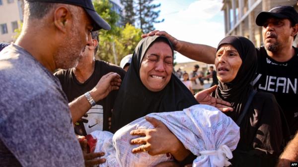 A woman mourns as she holds the shrouded body of her child who was killed during an Israeli strike on a school housing displaced Palestinians in Gaza City, Sept. 21, 2024.